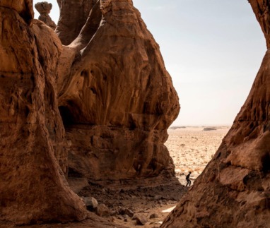 Man wandelt tussen imposante rode rotsformaties in de Adrar-woestijn van Mauritanië.