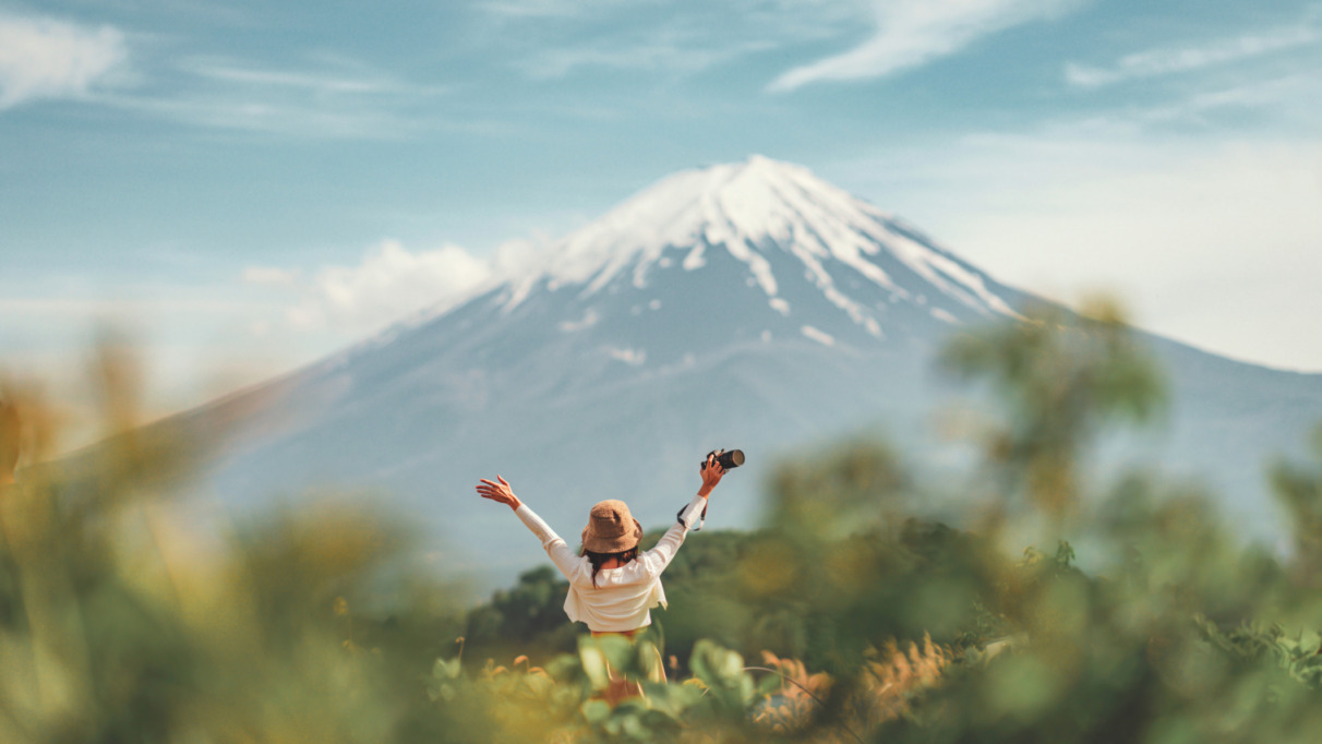 Blije reizigster staat met armen gespreid bij Kawaguchiko meer met Mount Fuji op de achtergrond in Japan