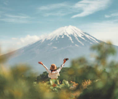 Blije reizigster staat met armen gespreid bij Kawaguchiko meer met Mount Fuji op de achtergrond in Japan