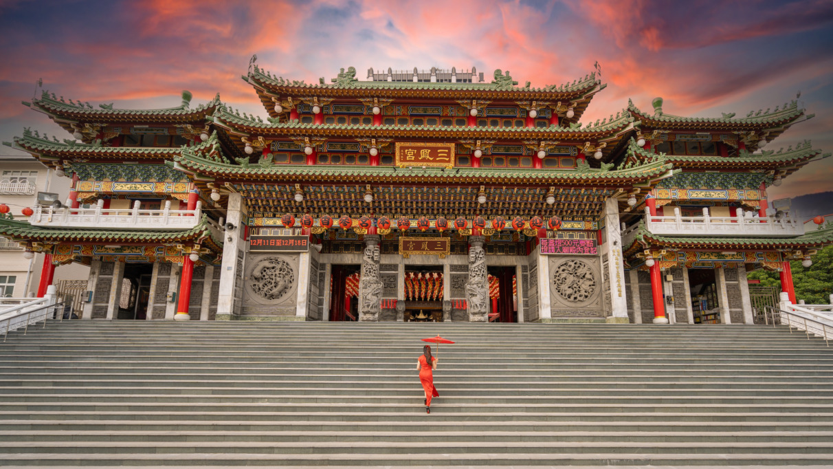 Aziatische vrouw in traditionele jurk op de trappen van de Sanfeng Tempel in Kaohsiung, Taiwan.