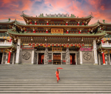 Aziatische vrouw in traditionele jurk op de trappen van de Sanfeng Tempel in Kaohsiung, Taiwan.