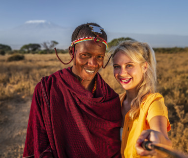 Blanke blonde vrouw met selfie met Masai-man in Kenia
