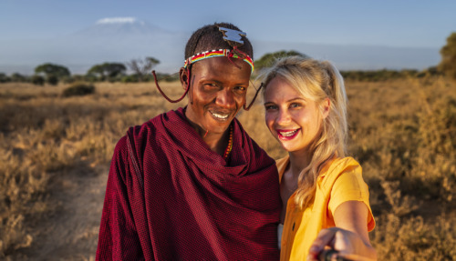 Blanke blonde vrouw met selfie met Masai-man in Kenia