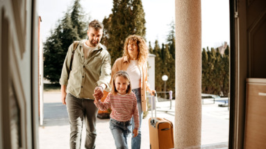 Blije familie voor een huis met een koffer