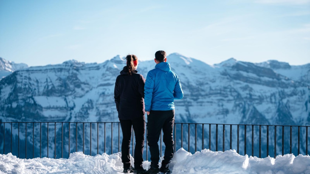 Twee wandelaars genieten van het uitzicht op besneeuwde bergtoppen in het Bregenzerwald, Oostenrijk