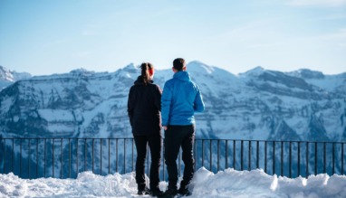 Twee wandelaars genieten van het uitzicht op besneeuwde bergtoppen in het Bregenzerwald, Oostenrijk