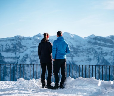 Twee wandelaars genieten van het uitzicht op besneeuwde bergtoppen in het Bregenzerwald, Oostenrijk