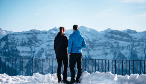 Twee wandelaars genieten van het uitzicht op besneeuwde bergtoppen in het Bregenzerwald, Oostenrijk