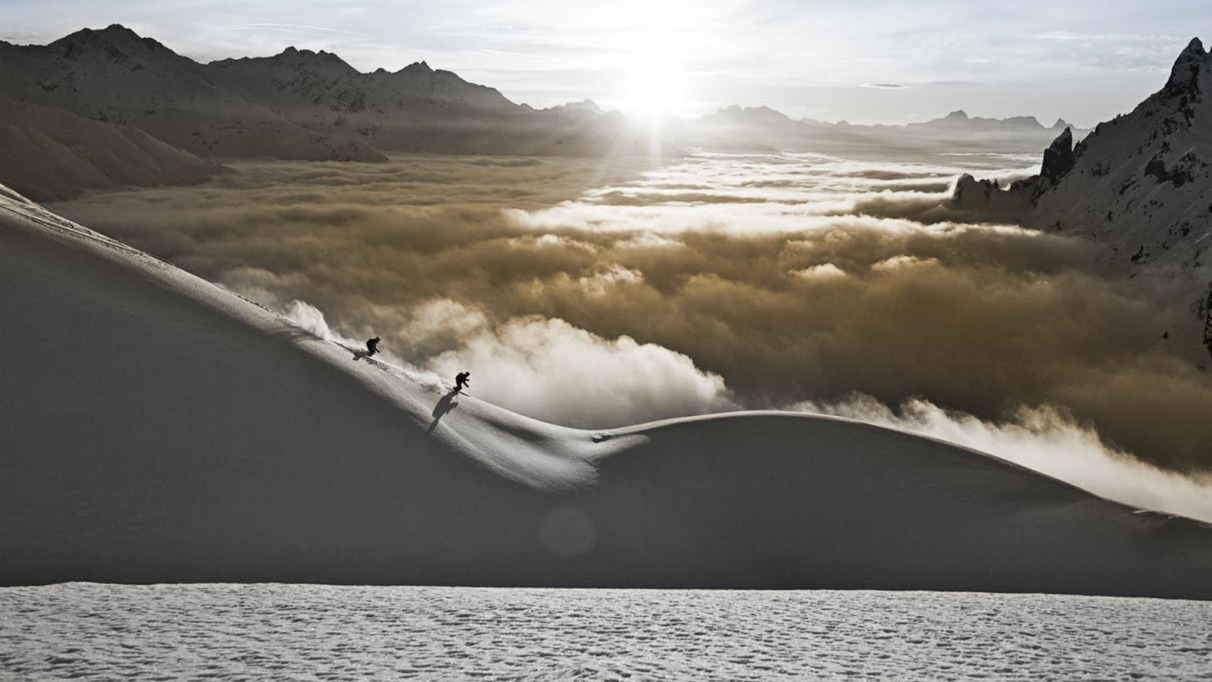 Twee skiërs dalen af door diepe sneeuw met uitzicht op de Alpen in de Arlberg, Oostenrijk