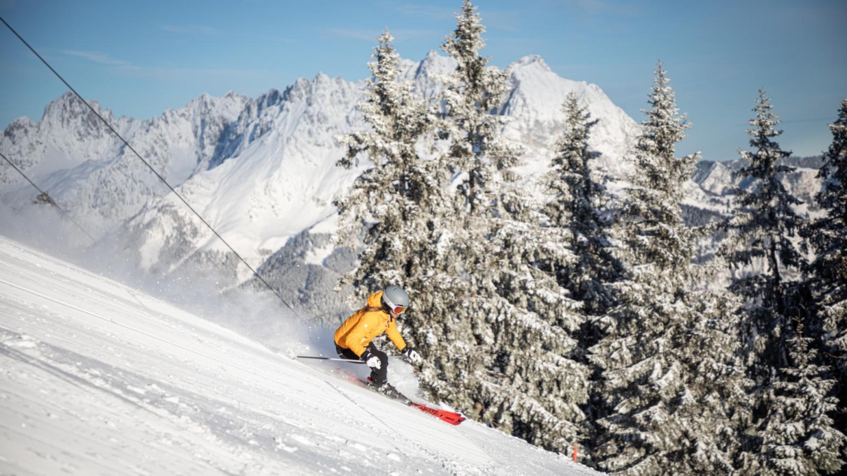Skiër in actie op de besneeuwde pistes van St. Johann in Tirol met uitzicht op de Wilder Kaiser, Kitzbüheler Alpen
