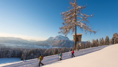 Wandelaars in de sneeuw in St. Johann in Tirol met uitzicht op de Wilder Kaiser in de Kitzbüheler Alpen