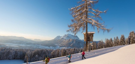 Wandelaars in de sneeuw in St. Johann in Tirol met uitzicht op de Wilder Kaiser in de Kitzbüheler Alpen