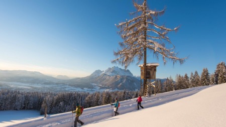 Wandelaars in de sneeuw in St. Johann in Tirol met uitzicht op de Wilder Kaiser in de Kitzbüheler Alpen