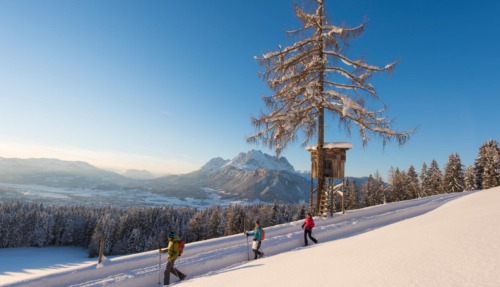 Wandelaars in de sneeuw in St. Johann in Tirol met uitzicht op de Wilder Kaiser in de Kitzbüheler Alpen