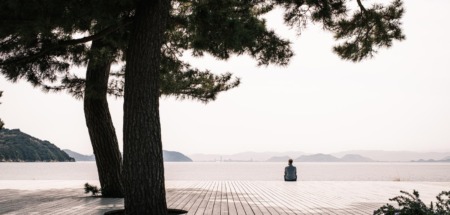 Persoon zit alleen op een houten platform aan zee op Naoshima, het kunsteiland van Japan.