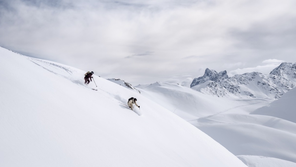Twee skiërs freeriden door de sneeuw in Arlberg, Oostenrijk