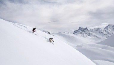Twee skiërs freeriden door de sneeuw in Arlberg, Oostenrijk