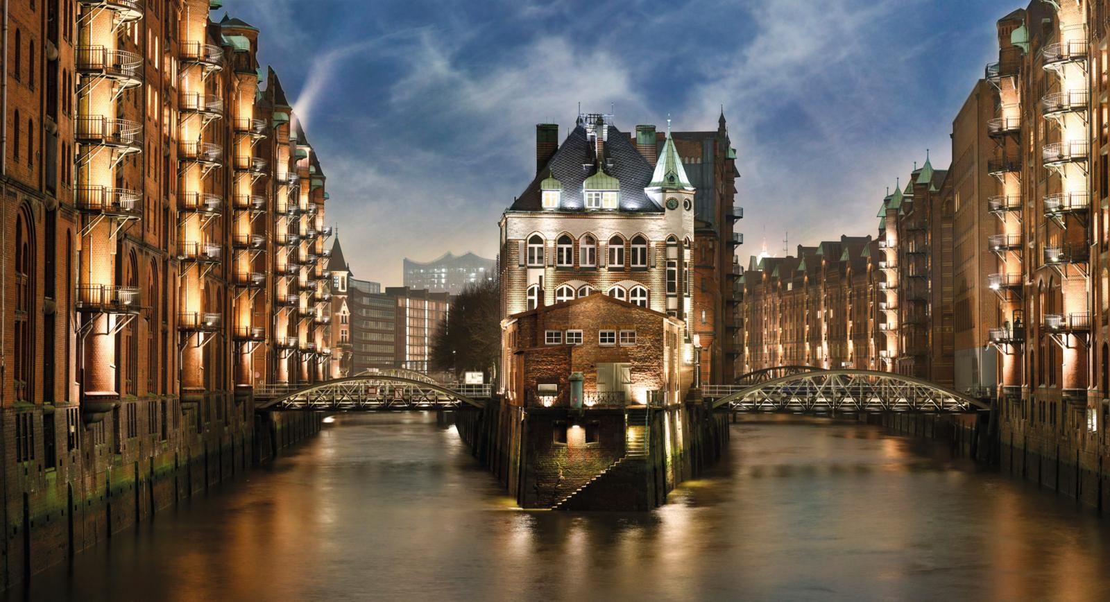 Verlicht Wasserschloss in de historische pakhuizenwijk Speicherstadt in Hamburg bij avond.