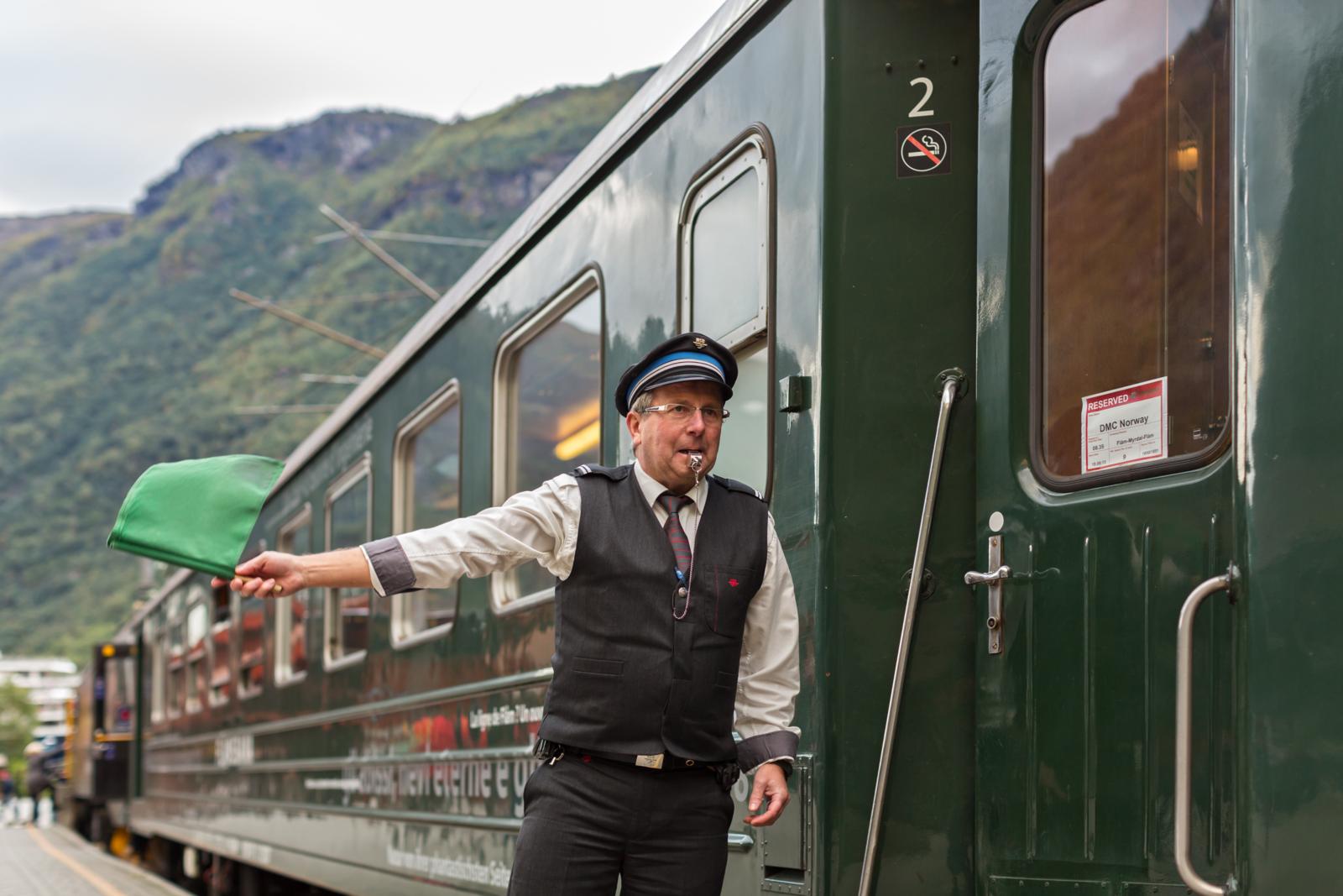 Conducteur met groene vlag bij de iconische Flåmsbana in Noorwegen.