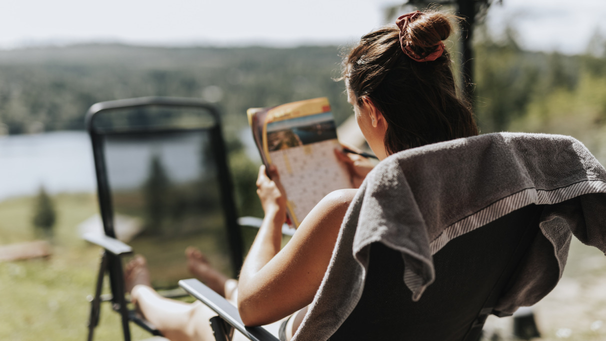 Vrouw puzzelt met kruiswoordraadsel in de tuin