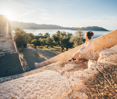 Reiziger geniet van zonsondergang in het antieke theater van Kaş met uitzicht op de Middellandse Zee, Turkije