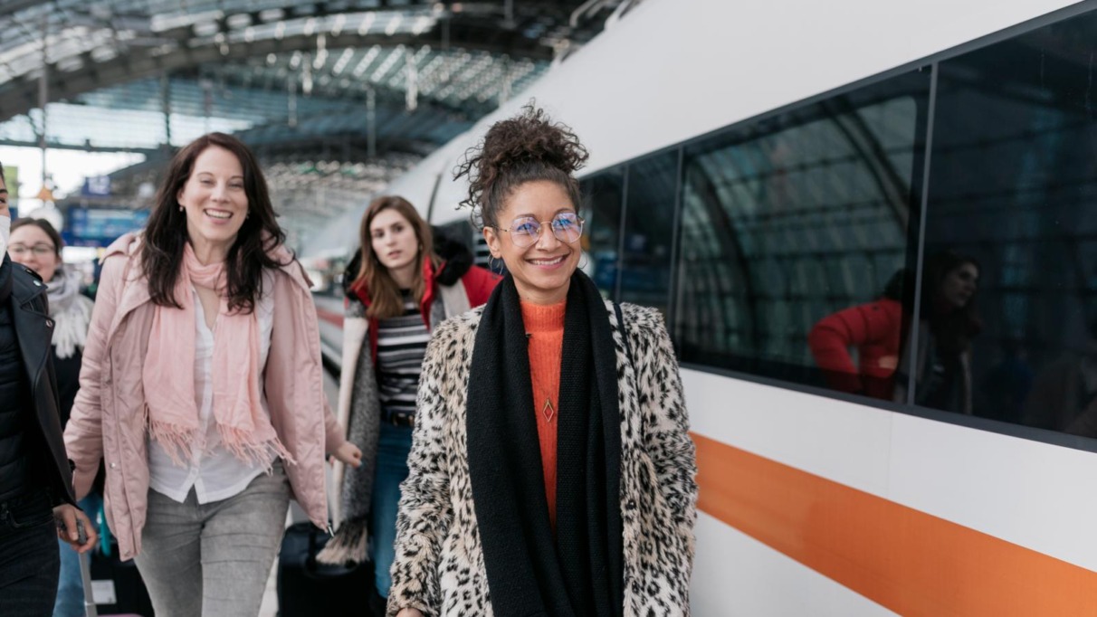 Drie vrouwen lopen op Duits treinstation om de Deutsche Bahn te nemen