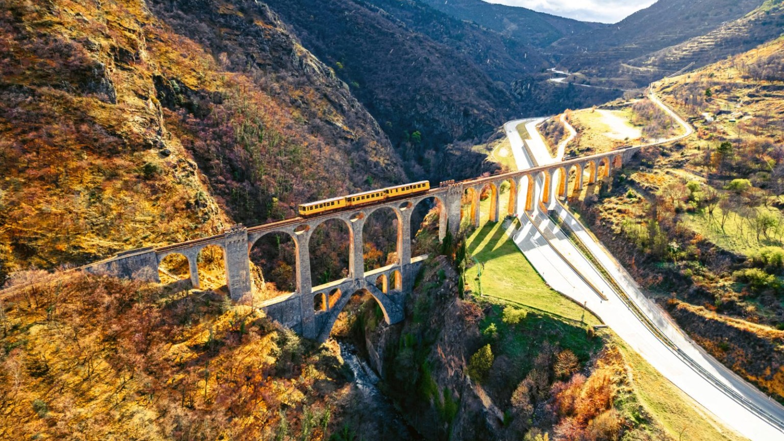 Iconische gele trein rijdt over het Séjourné-viaduct in de Franse Pyreneeën.