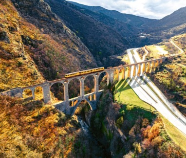 Iconische gele trein rijdt over het Séjourné-viaduct in de Franse Pyreneeën.