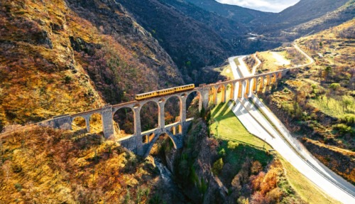 Iconische gele trein rijdt over het Séjourné-viaduct in de Franse Pyreneeën.