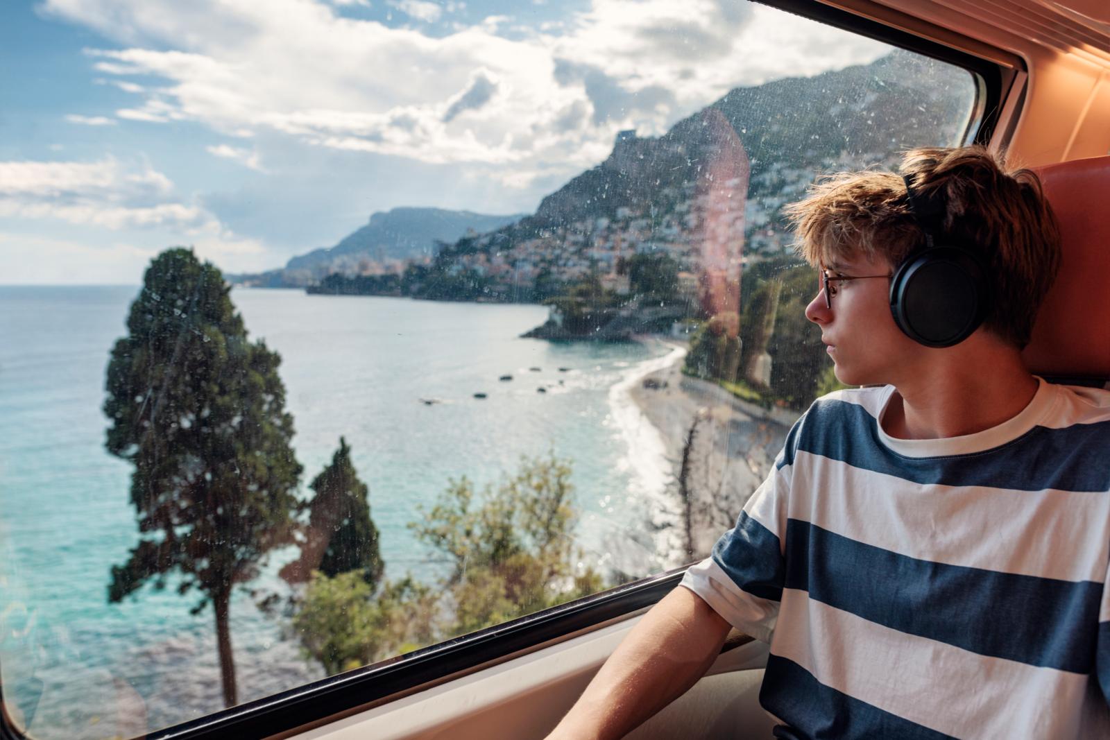 Jongen met koptelefoon kijkt uit de trein naar de kust van Zuid-Frankrijk.