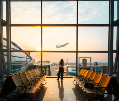 Een jonge vrouw kijkt naar een opstijgend vliegtuig op de luchthaven
