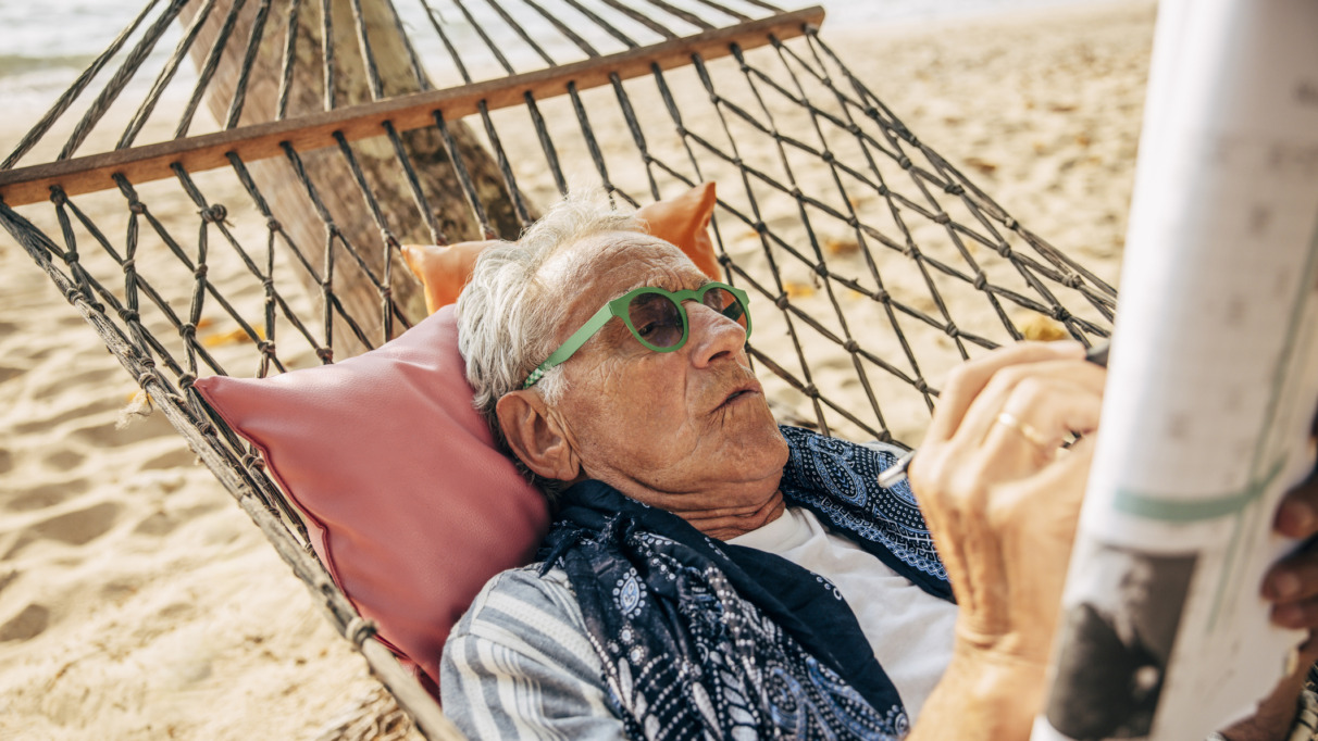 Bejaarde man in hangmat puzzelt met kruiswoordraadsel