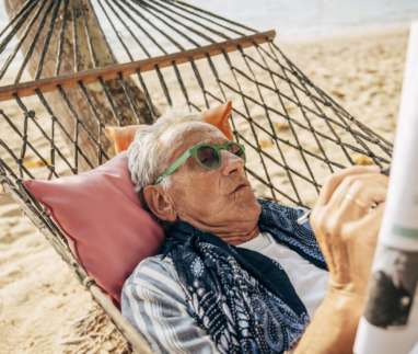 Bejaarde man in hangmat puzzelt met kruiswoordraadsel