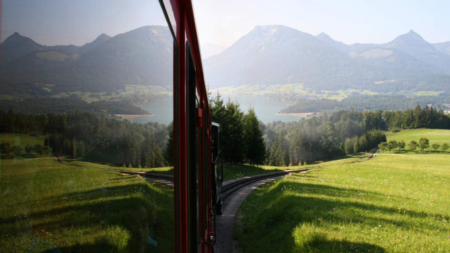 Uitzicht vanuit een rode tandradtrein op de Wolfgangsee en de omliggende bergen in Oostenrijk.