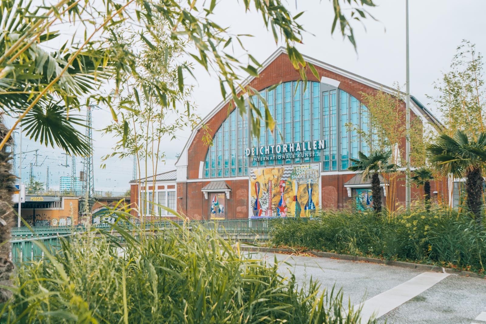 Buitenaanzicht van de Deichtorhallen in Hamburg, een centrum voor hedendaagse kunst, omgeven door groen.