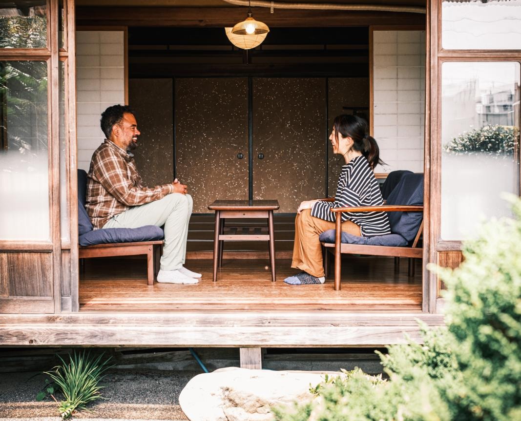 Twee gasten zitten tegenover elkaar in een traditioneel houten huis bij Hostel Kochi-no-ya in Aki, Shikoku, Japan