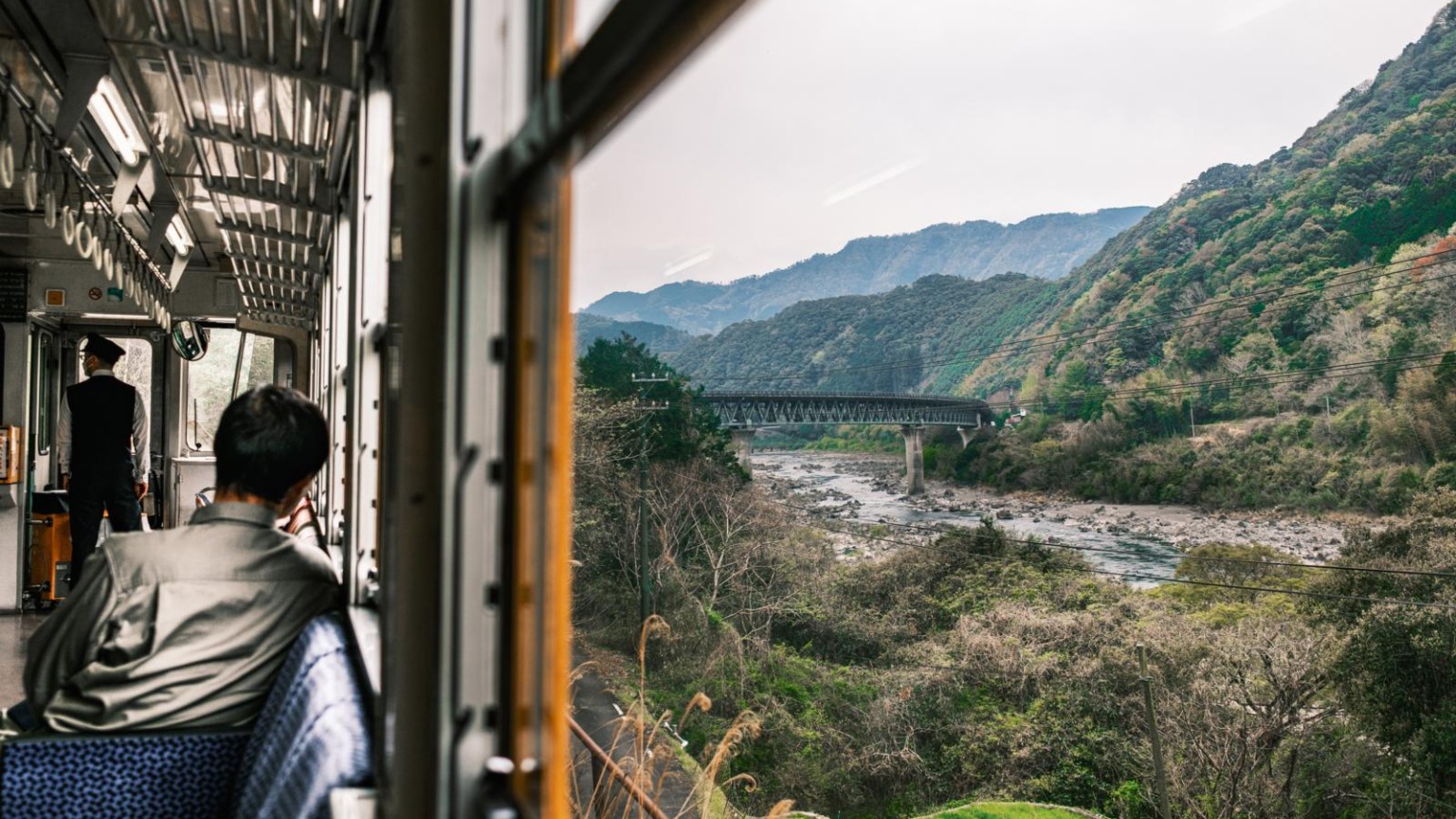 Uitzicht vanuit de Shiman Torocco Trolley in Shikoku, Japan, met rivierlandschap, bergen en spoorbrug