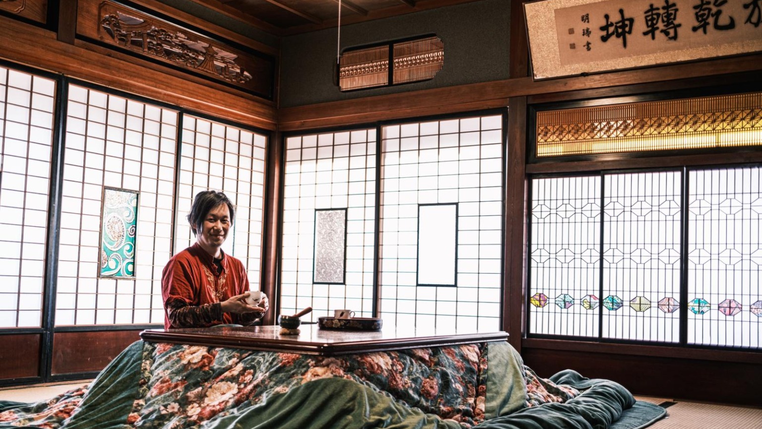 Man bij een lage tafel met een kopje thee in een traditioneel Japans huis in Iyo-Iwaki, Shikoku