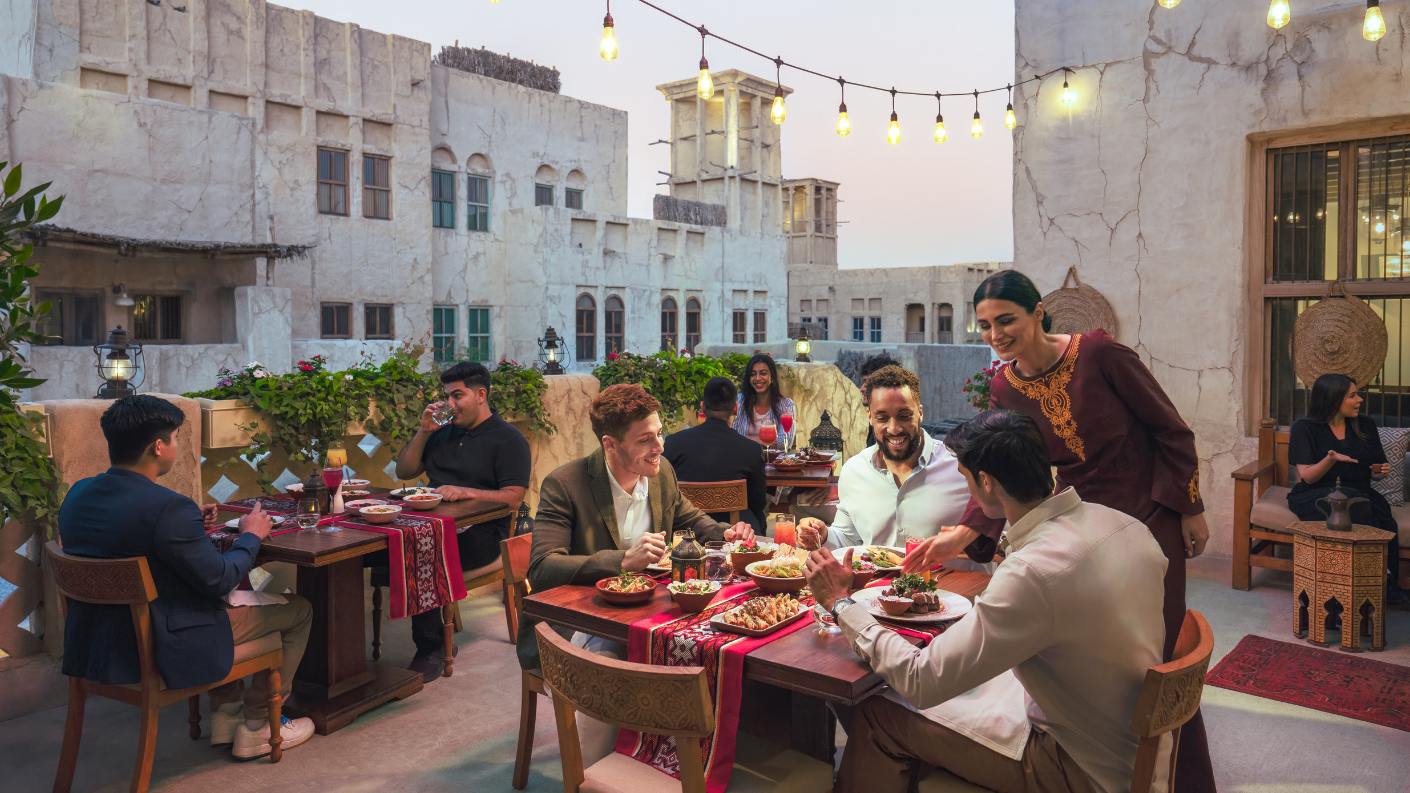 Mensen dineren op een sfeervol verlicht dakterras in Al Seef, Dubai.