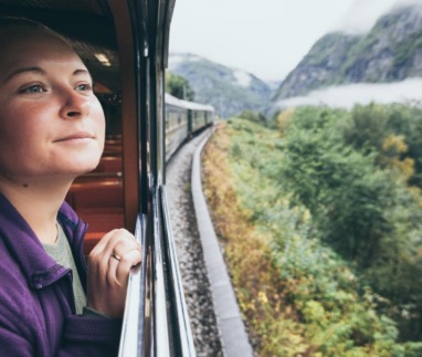 Vrouw kijkt uit het raam van een trein in Noorwegen