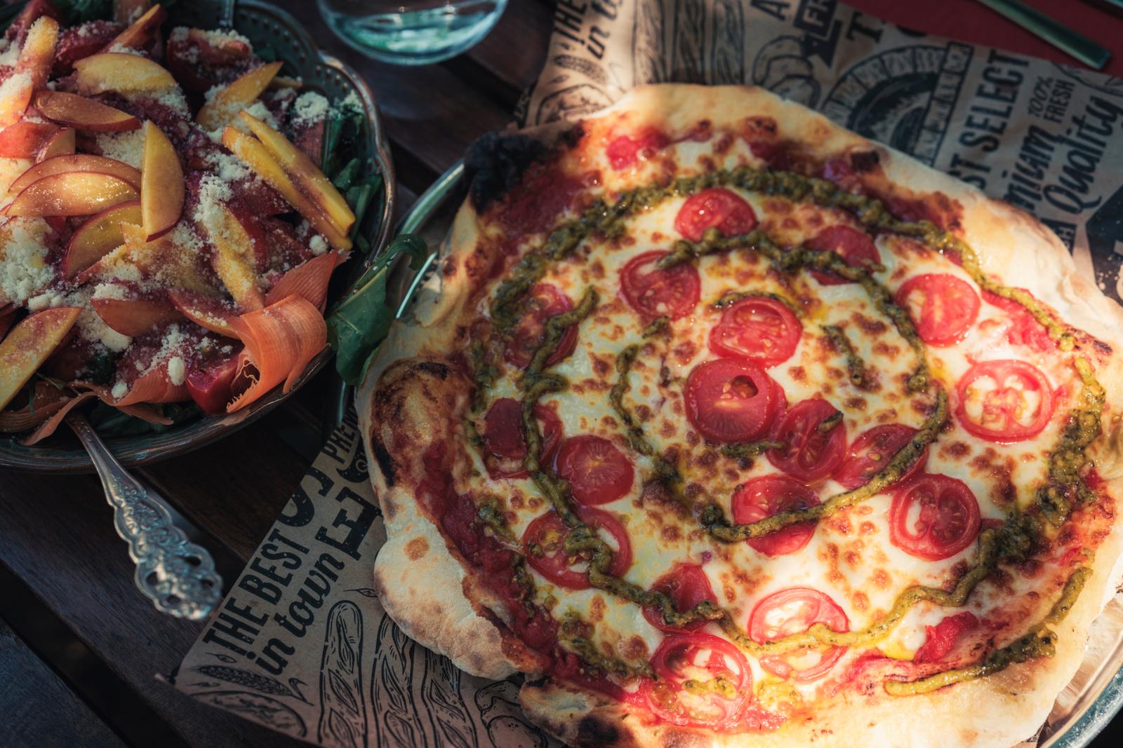 Ambachtelijke pizza met tomaat en pesto, geserveerd met verse salade bij Gupseden Pizza in Turkije