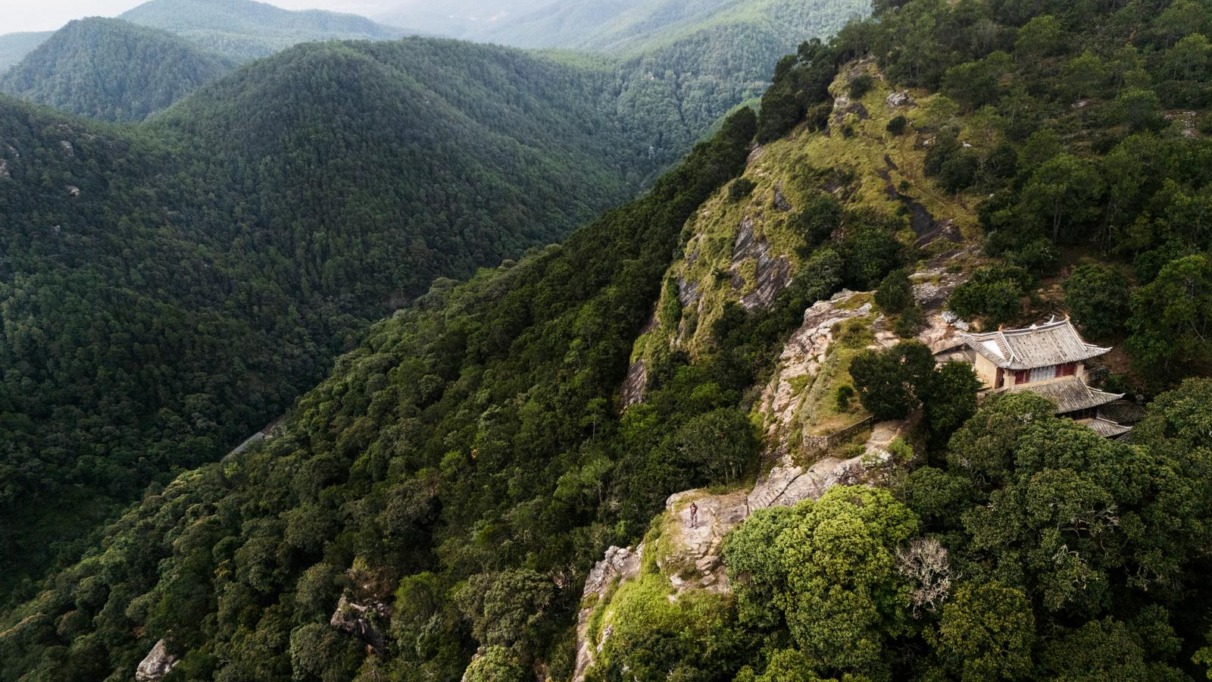 Luchtfoto van een afgelegen tempel op een bergrug bij Shaxi in Yunnan, China, omgeven door dichtbegroeide groene heuvels