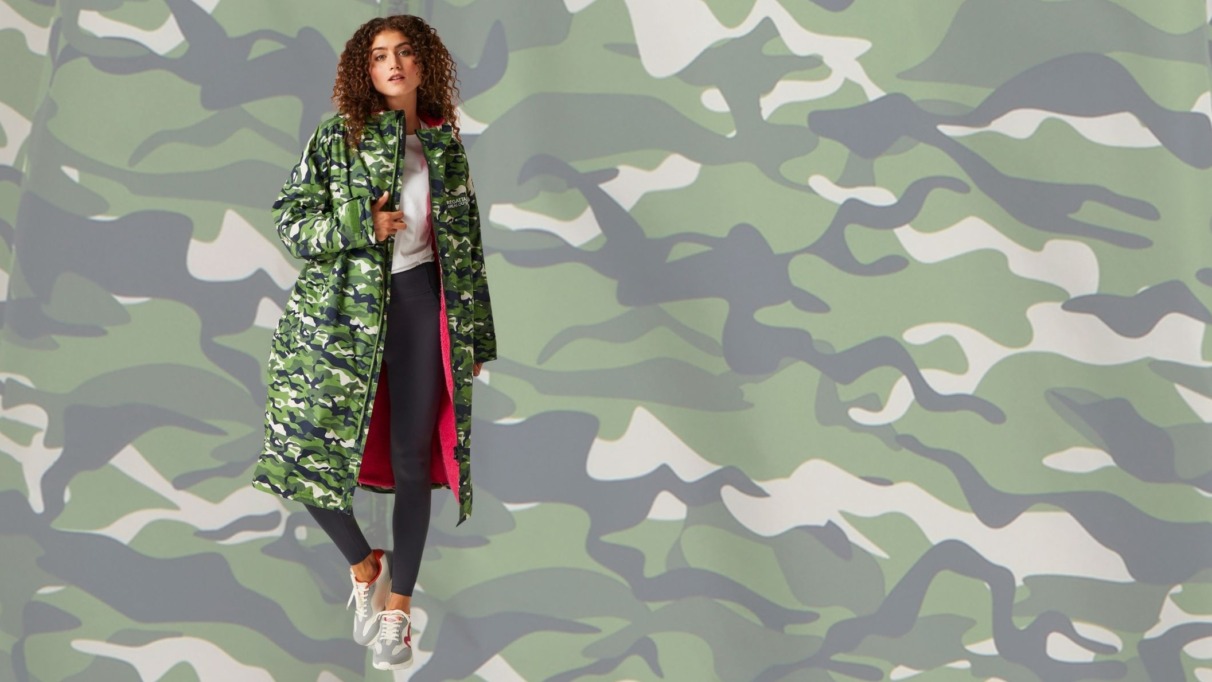 Vrouw draagt lange camouflagejas met roze voering voor reisliefhebbers die droog én stijlvol willen blijven