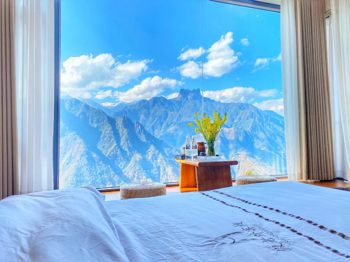 Hotelkamer van Laomudeng Jialaowai Chinese Inn met groot raam en uitzicht op de bergtoppen in Yunnan, China
