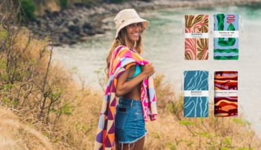 Vrouw met kleurrijke Buvanha-handdoek bij het water, met verschillende dessins van duurzame strandhanddoeken