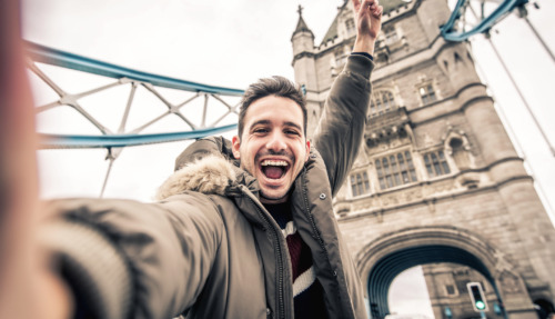 Man staat vrolijk op de Towerbridge in Londen. De stad is verkozen tot beste wereldstad van 2026.