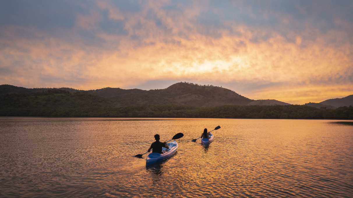 Twee mensen kajakken bij zonsondergang