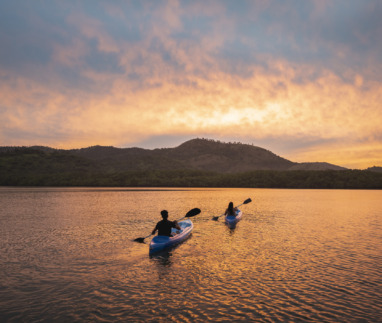 Twee mensen kajakken bij zonsondergang