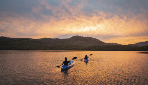 Twee mensen kajakken bij zonsondergang