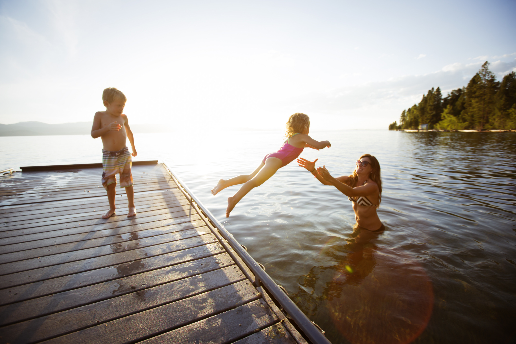 Een jong meisje dat in Flathead Lake in de armen van haar moeder springt.